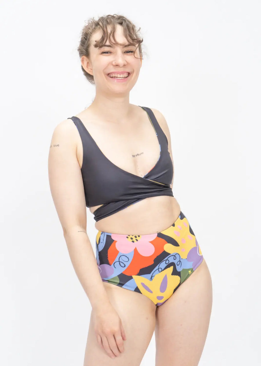 High-waisted bikini bottom with colorful abstract print paired with a dark gray swim top.